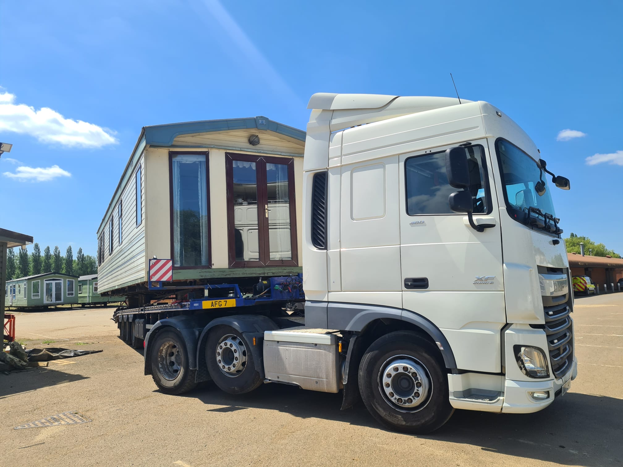 White lorry hauling a caravan structure