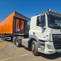 White truck with a static caravan loaded on the back