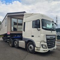 White transport vehicle with a static caravan onboard