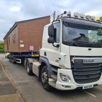 White truck with a large static caravan on its bed