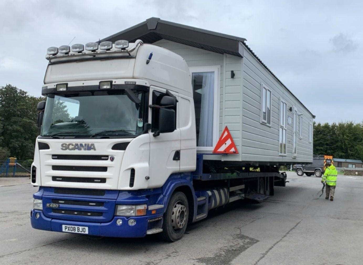 White flatbed truck with a caravan secured on top